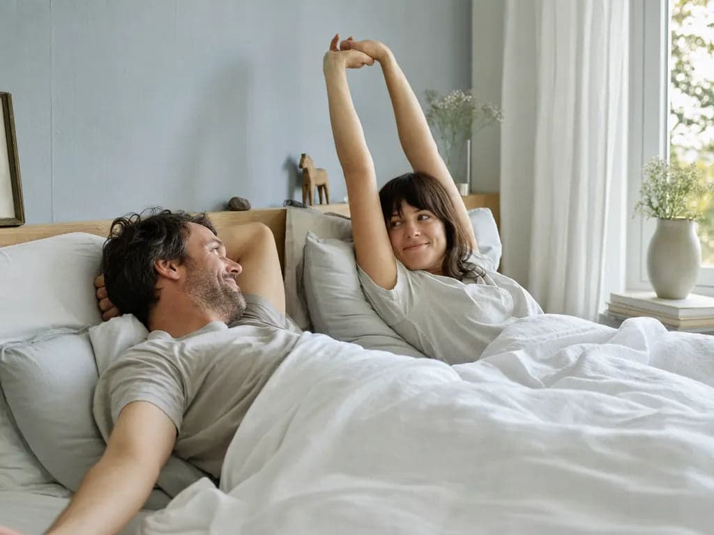 Ausgeschlafenes Paar am Morgen im hellen Schlafzimmer